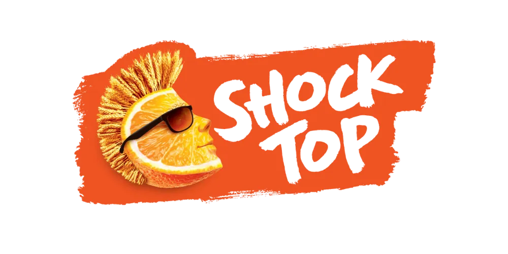 לוגו של Shock Top בצורת פלח תפוז עם מוהוק, משקפי שמש וטקסט כתום על רקע כתום.